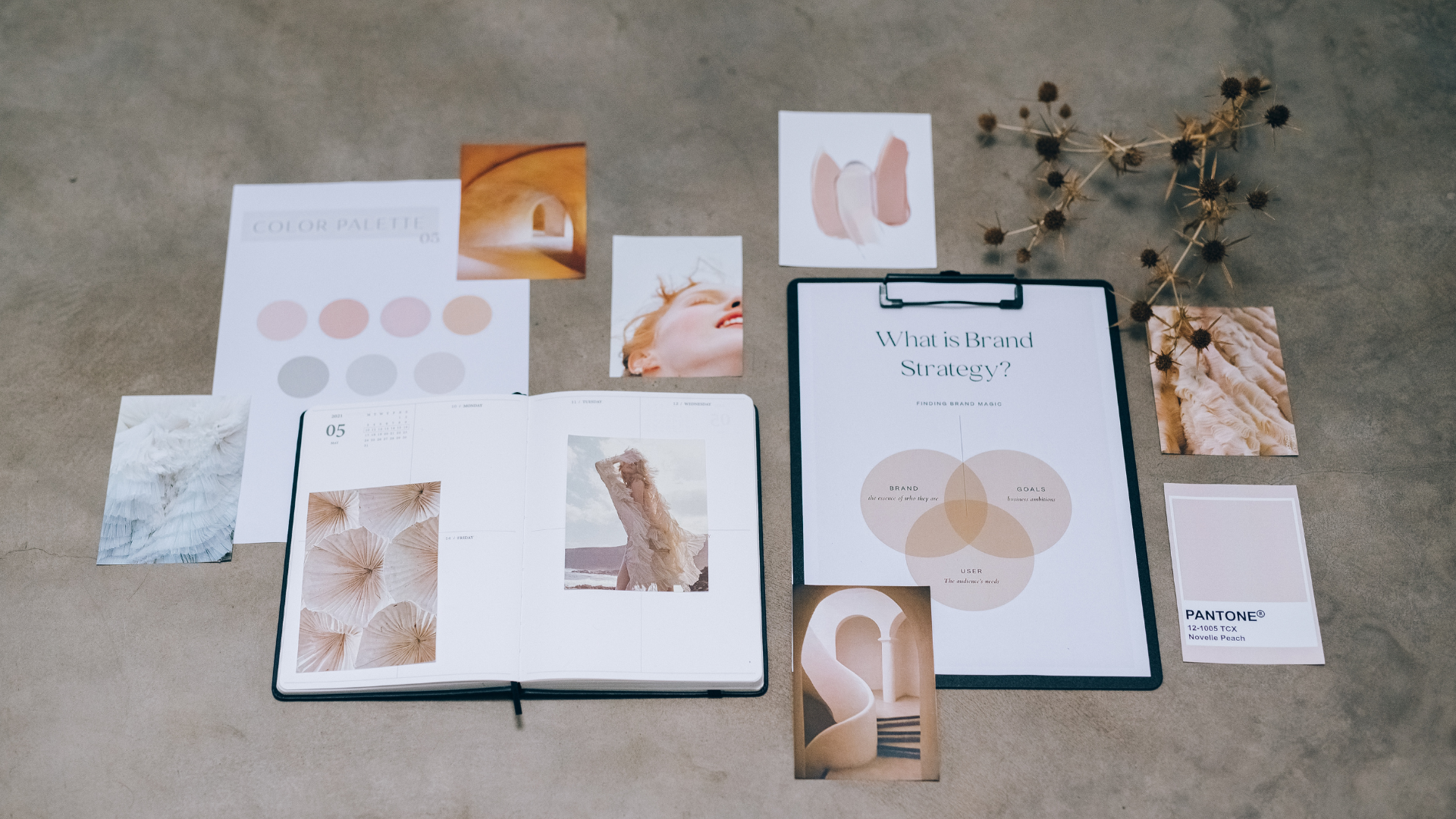 Flat lay of brand strategy materials, including a color palette, photos, and a notebook, showcasing creative design and planning.