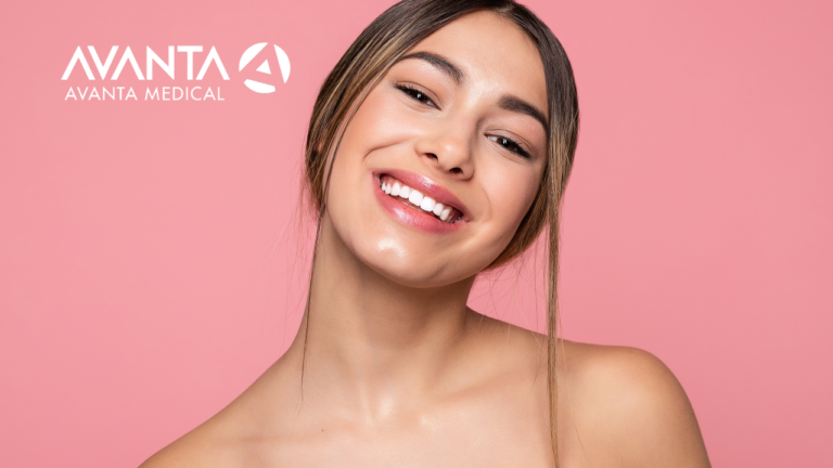 Smiling woman with glowing skin against a pink background, representing the results of advanced skincare and aesthetic treatments by AVANTA Medical